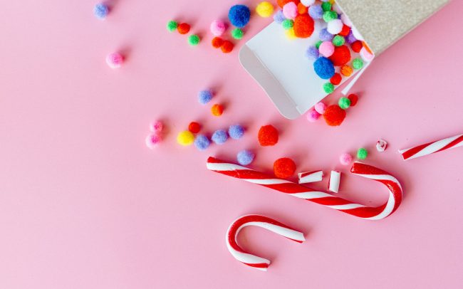 A photo of candy canes and sweets on a pink background